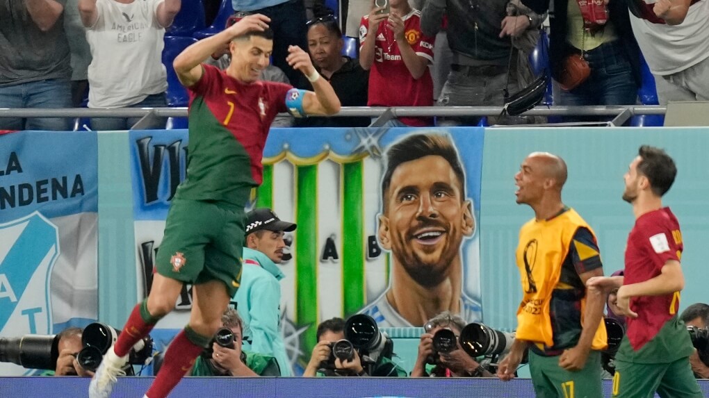 Portugal's Ronaldo does the "siu" celebration after scoring a penalty against Ghana in the World Cup, as a poster of Messi watches in wonder